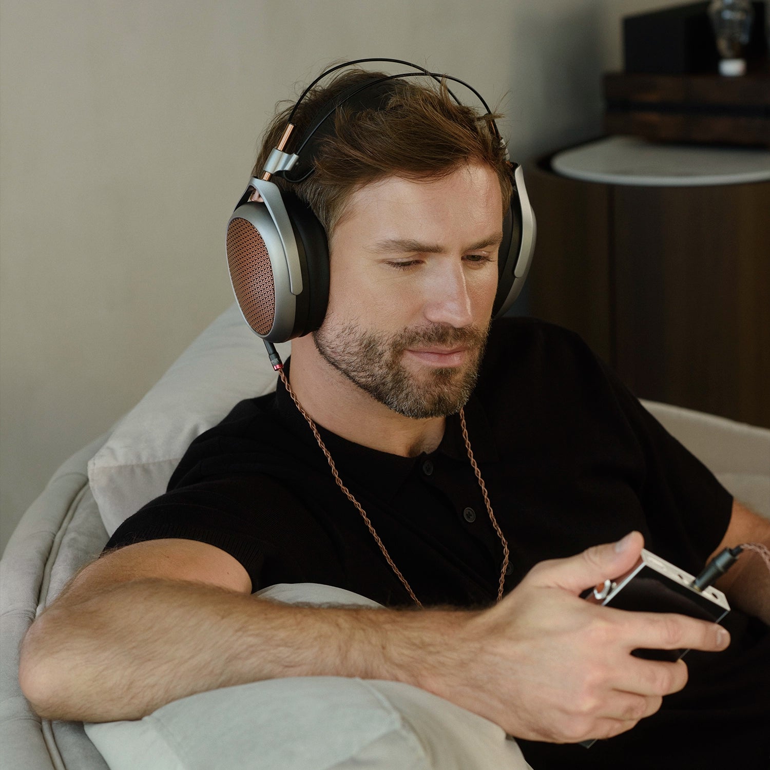 Man listening to Meze Audio POET planar magnetic open-back headphones copper ear cups premium build indoors