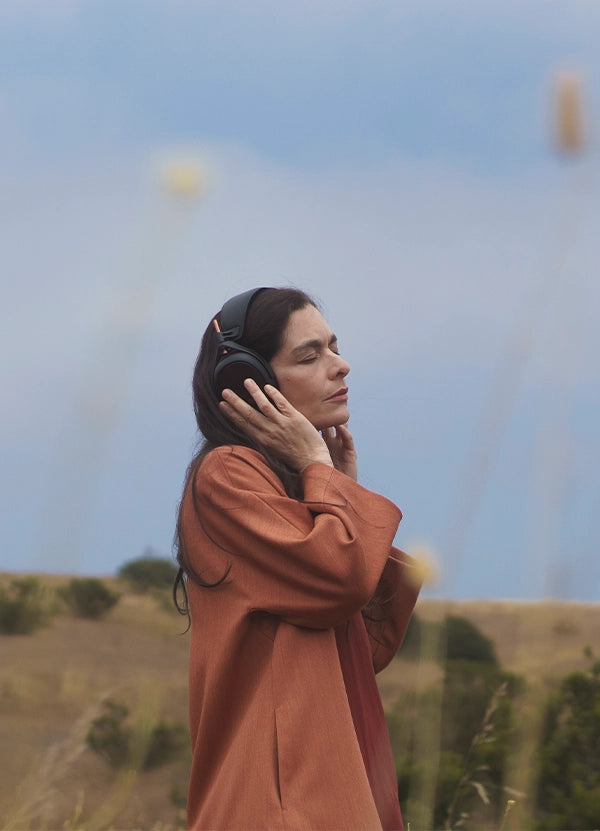 Woman listening to Meze Audio Liric closed back planar magnetic headphones outdoors
