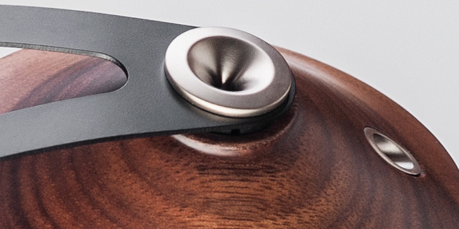 Detailed close-up showing the craftsmanship of the walnut wood ear cups of these closed-back audiophile headphones, emphasizing premium build quality.