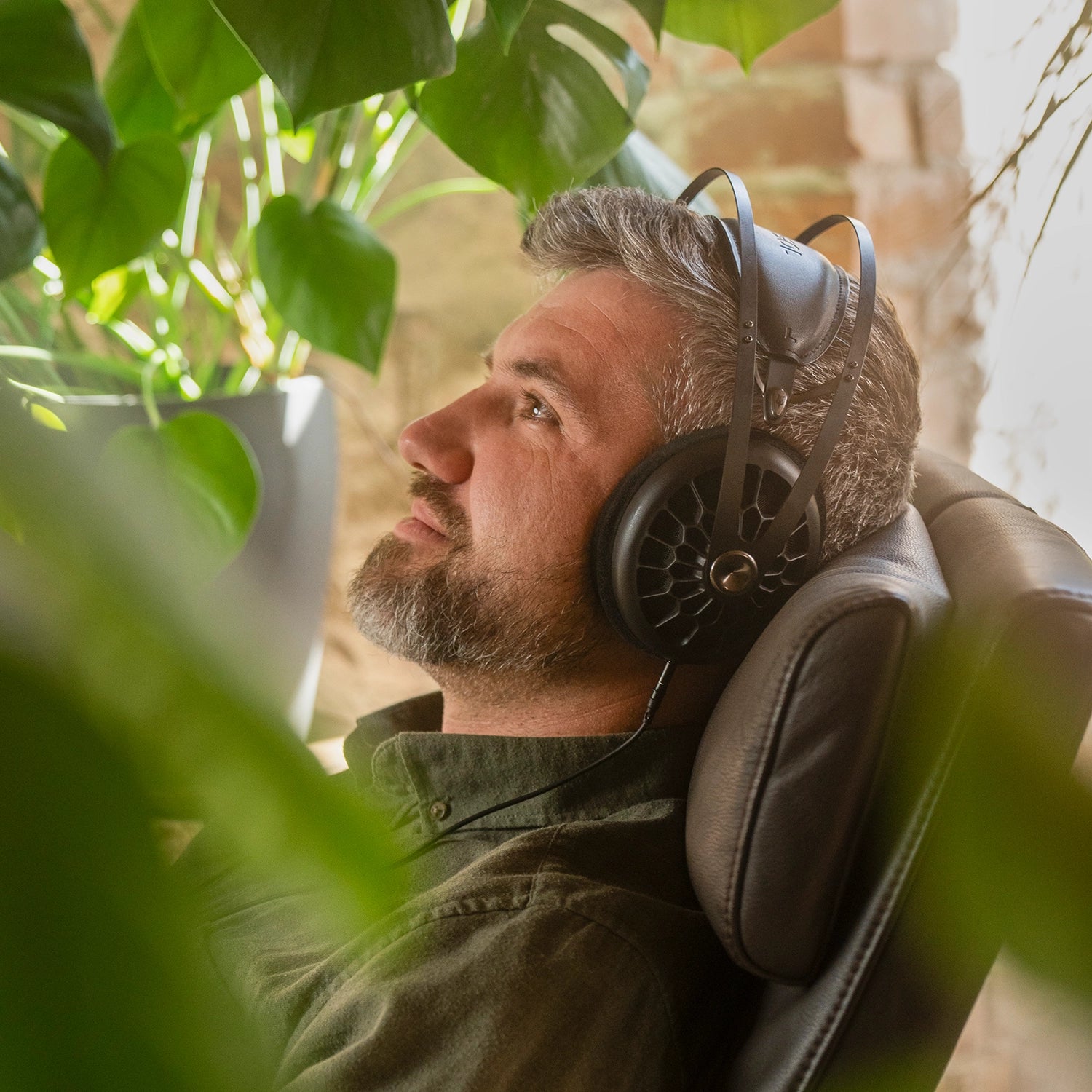 Meze Audio 105 AER best open back high fidelity audiophile premium headphones worn by man inside while sitting on an armchair 