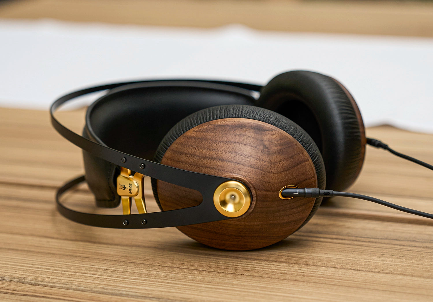 Meze Audio 99 Classics Walnut Gold closed back audiophile headphones on a wooden desk