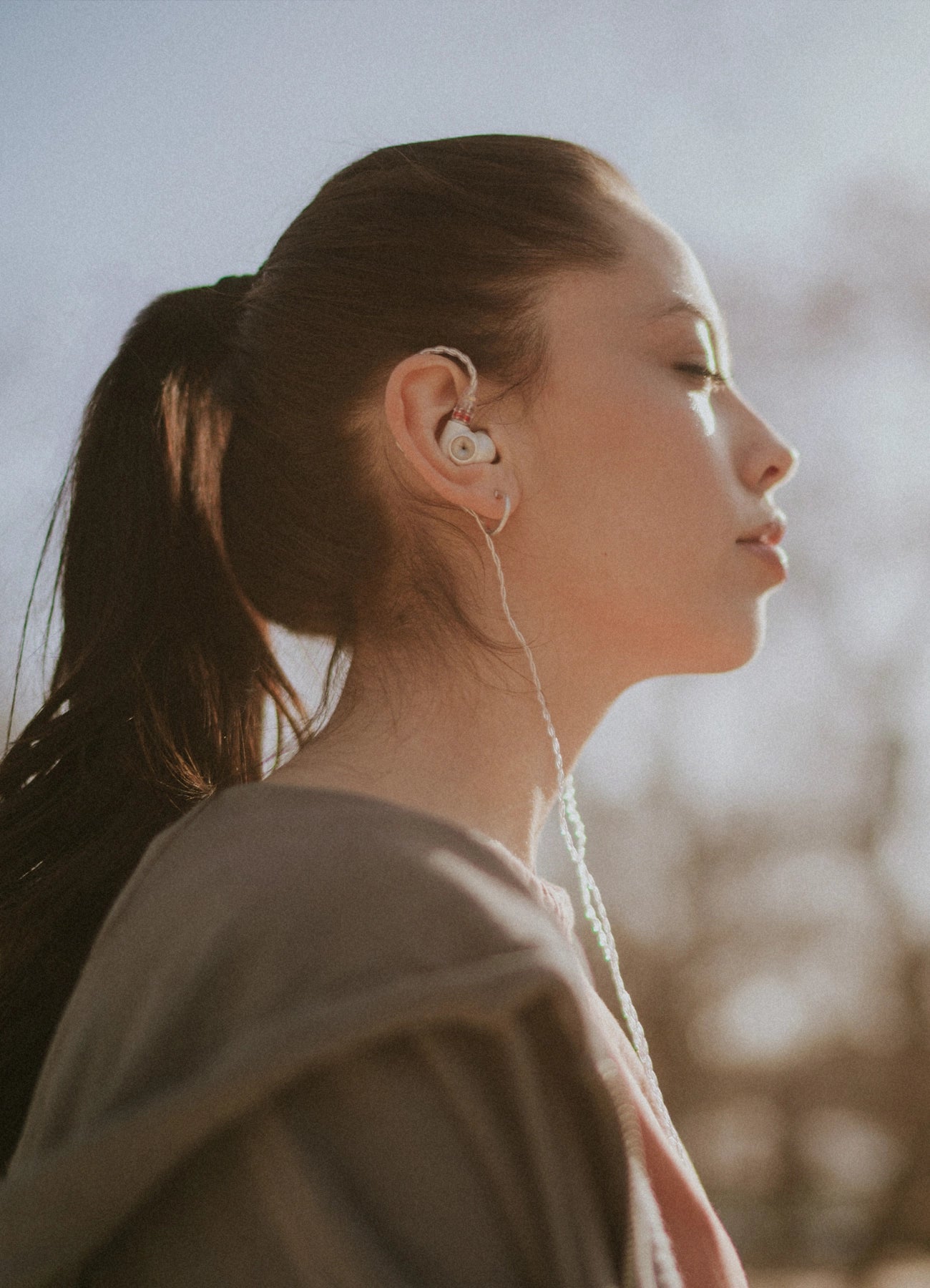 Young woman wearing the Meze Audio Alba best wired earbud headphones while walking in the forest