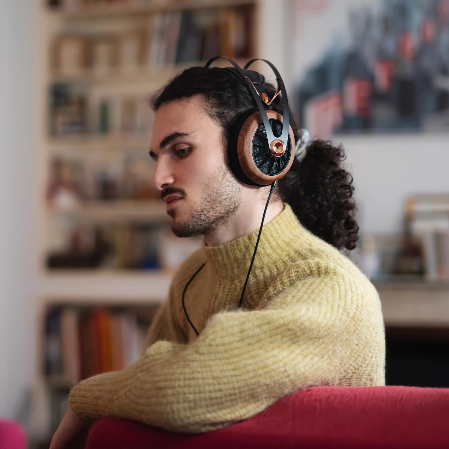 Man in yellow jumper sitting and listening to music on his Meze Audio 109 PRO wired head phones