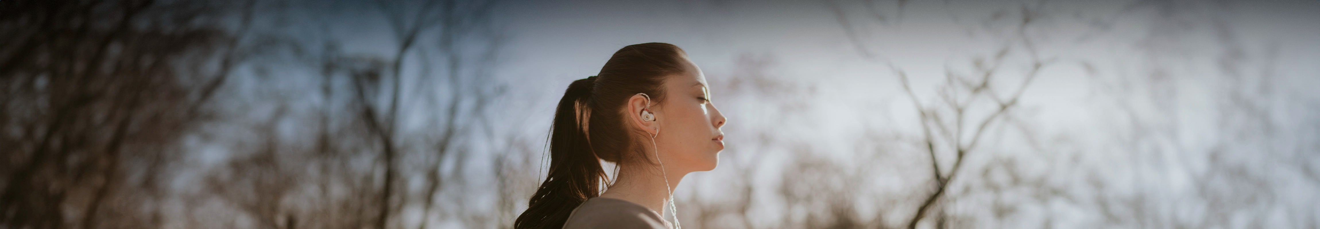 Young girl listening to music using the Meze Audio Alba dynamic driver audiophile in-ear wired earbuds