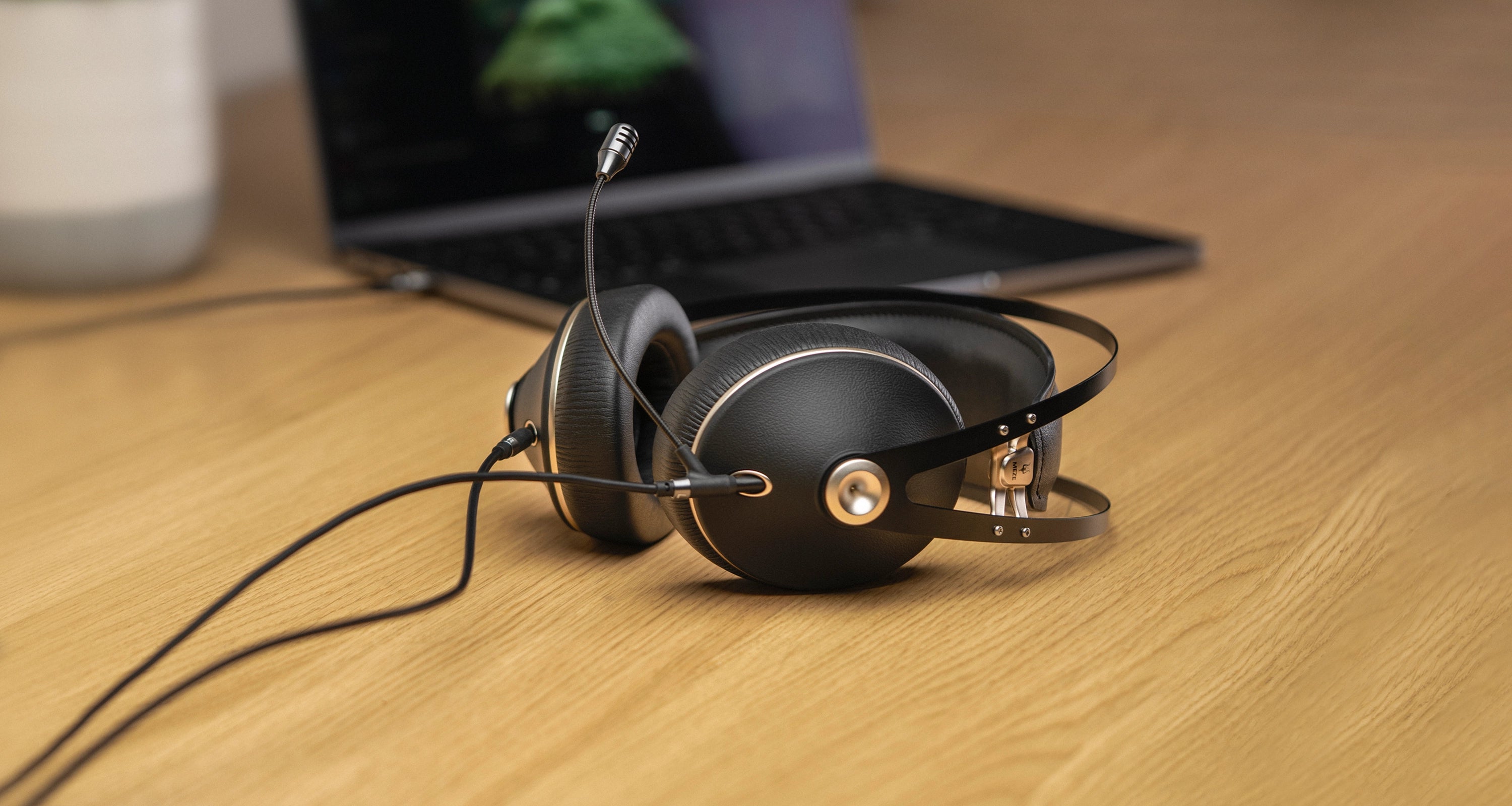 Meze Audio 99 Neo closed back Gaming Headset with Boom Mic on a desk in front of a laptop